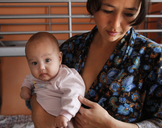 A single Tajik woman holds one of her twins in a shelter for women in crisis where she and other single women live outside Moscow