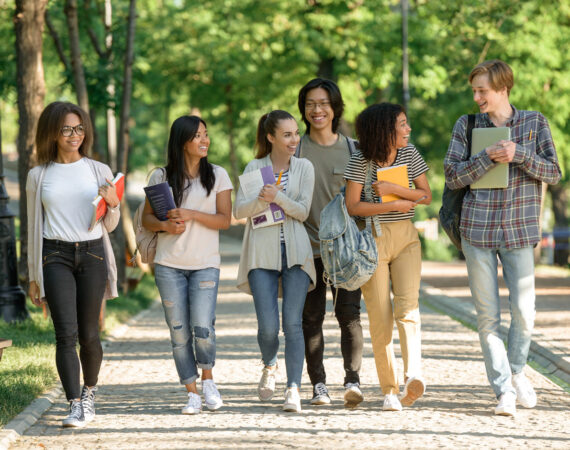 Multiethnic group of young cheerful students walking